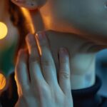 a close-up photo of a person holding their neck with a pained expression, highlighting the discomfort of a sore throat after a tooth extraction.