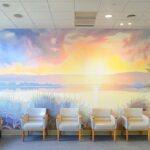 a serene dental clinic waiting room bathed in soft, natural light, featuring inviting, comfortable chairs and a peaceful mural of a sunlit landscape.