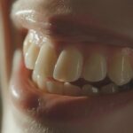 a close-up shot of a confident patient smiling brightly, showcasing their perfectly aligned mini dental implants against a soft-focus background of a modern dental clinic in lake worth, illuminated by warm, natural light.