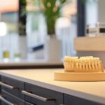 a pristine dental clinic showcases a gleaming dental implant model on a polished counter, bathed in soft, natural light that highlights its intricate details and emphasizes the importance of oral health maintenance.