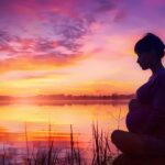 a serene lake worth landscape features a gently rippling lake at sunset, reflecting vibrant hues of orange and purple, with the silhouette of a concerned pregnant woman gazing thoughtfully into the distance, symbolizing the weight of healthcare decisions.