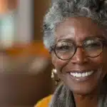 a radiant close-up of a confident individual showcasing a flawless smile, with vibrant lighting accentuating the natural shine of their dental implants against a softly blurred background.