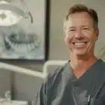 a radiant smile extends across a confident individual's face, showcasing flawless dental implants that embody durability and an inviting sense of well-being, set against a softly lit, serene backdrop.