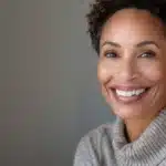 a radiant smile showcasing flawless dental implants under soft, warm lighting highlights the aesthetic transformation and confidence of the subject against a serene background.