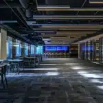 a sleek, modern office with minimalistic design features a large digital screen displaying vibrant data analytics, bathed in bright overhead lighting that highlights the dynamic energy of teamwork and innovation.