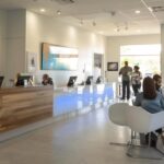 a bustling dental clinic waiting room filled with diverse patients exploring affordable denture options on tablets, with professional dental posters and a modern reception desk creating a welcoming atmosphere.