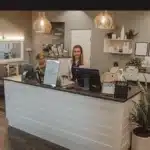 a modern dental clinic in downtown tyler, texas, showcasing a welcoming reception area with sleek furnishings, a friendly staff member greeting patients, and informative signage about affordable dentures, all bathed in warm, inviting lighting.