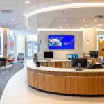 a sleek, modern dental clinic with a bright, sterile atmosphere showcasing a digital consultation area where a patient is exploring innovative, cost-effective alternatives to traditional dental implants on a large screen, surrounded by advanced dental technology.
