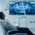 Image of an elderly person examining their teeth, contemplating when to get dentures.
