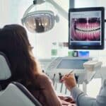 a focused dental clinic interior features a concerned patient seated in a modern examination chair, with a dental professional explaining potential complications of implants using a digital model displayed on a sleek tablet, bathed in bright, clinical lighting.