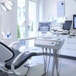 a focused dental consultation room features a patient sitting thoughtfully in a modern chair as an attentive dentist discusses the pros and cons of dental implants, with advanced dental equipment and informative charts visibly presented in the background.