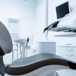 a modern dental clinic featuring a sleek, high-tech dental chair with bright overhead lighting, emphasizing the importance of tooth implants in a clean, sterile environment.