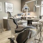 a modern dental office interior showcases a confident patient discussing affordable dental implant options with a knowledgeable dentist, surrounded by advanced dental equipment and sleek, professional decor.