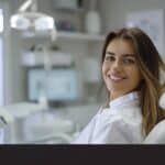a sleek dental clinic interior showcases a confident patient examining their radiant smile in a modern mirror, illuminated by bright, clinical lighting, highlighting the seamless integration of dental implants as a natural part of their dental health.