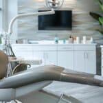 a sleek, modern dental clinic interior showcases a confident individual discussing dental implants with a dental professional, highlighting the intersection of oral health and intimate relationships in a vibrant, engaging atmosphere.