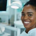 a close-up portrait of a confident individual smiling broadly in a sleek, modern dental office, highlighting their seamless dental implants against a backdrop of pristine white dental equipment and soft, diffused lighting.