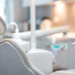 a modern dental clinic showcases a confident patient smiling brightly with their implant-supported dentures prominently featured, while innovative dental technology and tools are stylishly arranged in the background, emphasizing precision and care.