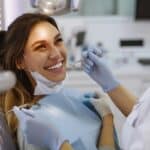 a sleek dental clinic interior showcases a confident patient smiling brightly next to a dental professional holding a state-of-the-art tooth implant, highlighting modern dental technology and successful outcomes.