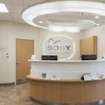 a modern dental clinic in fort worth, texas, featuring a bright and welcoming reception area with friendly staff members ready to assist patients seeking affordable gum disease treatment.
