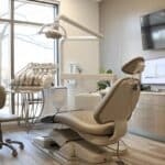 a serene dental office interior showcases a patient comfortably reclining in a modern dental chair, surrounded by sophisticated equipment and soothing, ambient lighting, emphasizing a sense of relief and care following dental implant procedures.