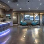 a modern, inviting dental office in mansfield, texas features a warm reception area with a friendly atmosphere, showcasing a sleek digital display highlighting affordable emergency dental care services.