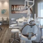 a sleek, modern dental office features a confident patient smiling broadly, showcasing a perfectly restored smile with dental implants, while a meticulous dentist discusses the impressive benefits of this tooth replacement option in a sterile, well-lit environment.