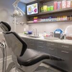 a sleek, modern dental office with a pristine dental chair under bright, clinical lighting, featuring a vibrant display of foods such as hard candies, crunchy snacks, and dark-colored beverages highlighted on a nearby countertop, symbolizing the dietary restrictions after dental implants.