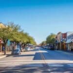 a bustling urban street in tyler, texas, showcasing a bright storefront with bold signage advertising affordable root canal services, surrounded by diverse pedestrians and modern buildings under a clear blue sky.