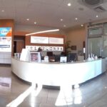 a modern dental clinic in mansfield, tx features a polished consultation area where patients engage with experienced prosthodontists, surrounded by state-of-the-art digital scanning equipment and a display showcasing various denture options, under bright, inviting lighting.