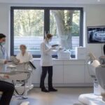 a modern dental clinic in mansfield showcases a confident patient consulting with an experienced dentist, surrounded by advanced imaging technology and detailed dental models illustrating the transformative process of dental implants.
