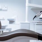 a polished dental consultation room, featuring a sleek modern dental chair under bright clinical lighting, where a dentist explains advanced treatment options for dental implants and bridges to a patient, emphasizing the importance of gum health.