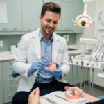 Dental professional demonstrating dental implant care techniques in a bright dental office