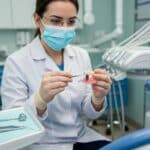 Dental professional examining a dental implant in a clinical setting