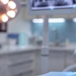 a modern dental office features a close-up view of a state-of-the-art dental implant setup, showcasing a titanium screw alongside a sleek porcelain crown on a clinical treatment surface, illuminated by bright, focused overhead lighting to emphasize the precision and sophistication of dental restoration technology.