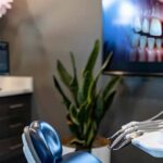 a modern dental clinic setting features a confident middle-aged patient consulting with a dentist next to a sleek digital display showcasing dental implant technology, highlighting both comfort and advanced care.
