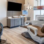 a sleek, modern dental clinic in mansfield, tx, featuring a high-tech examination room with advanced imaging equipment, a comfortable dental chair, and a radiant display showcasing the transformative process of dental implants.