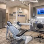 a sleek, modern dental clinic interior showcases a knowledgeable dentist consulting with a patient about advanced dental implant care, highlighted by state-of-the-art diagnostic equipment and a clean, professional atmosphere.
