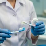 Dental professional demonstrating dental implant cleaning techniques with toothbrush and floss