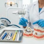 Dental professional demonstrating care techniques for dental implants, bridges, and dentures