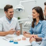 Dental professional explaining dental implants and bridges to a patient in a modern dental office