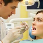 Dental professional examining a dental implant with a patient in a clinical setting