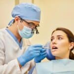 Dental professional examining a dental implant with a patient in a clinical setting